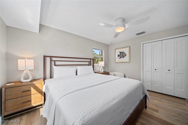 bedroom featuring ceiling fan, a closet, wood finished floors, and visible vents