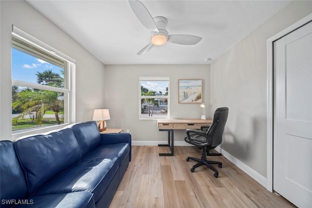 office space with light wood-type flooring, a ceiling fan, and baseboards