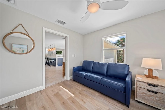 living room featuring visible vents, ceiling fan, baseboards, and wood finished floors