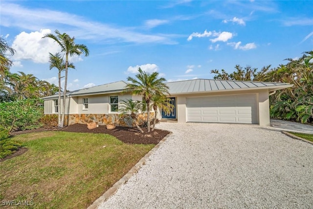 ranch-style house featuring a standing seam roof, driveway, an attached garage, and stucco siding