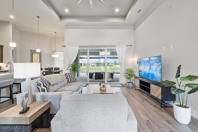 living room with a tray ceiling, sink, and a high ceiling