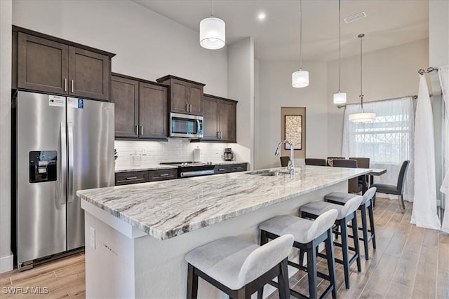 1142 SW 15th St, Cape Coral, FL 33991 - kitchen with appliances with stainless steel finishes, a sink, dark brown cabinets, a center island with sink, and tasteful backsplash