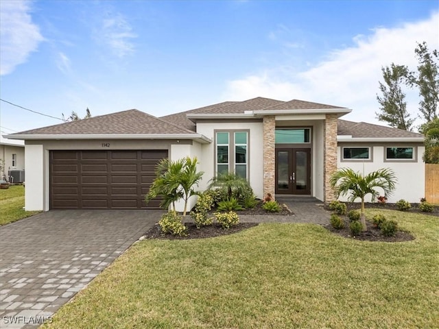 prairie-style home with french doors, a front lawn, central AC unit, and a garage