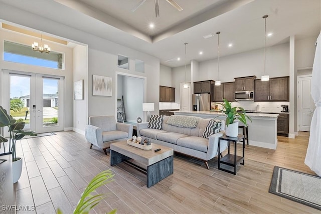 1142 SW 15th St, Cape Coral, FL 33991 - living room with a high ceiling, a chandelier, light wood-style flooring, baseboards, and french doors