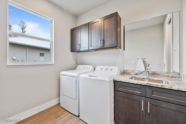 clothes washing area with washer and dryer, cabinets, and sink