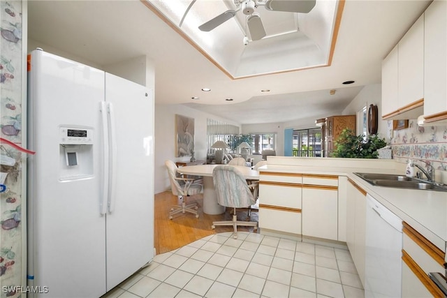 kitchen with kitchen peninsula, sink, white cabinets, and white appliances