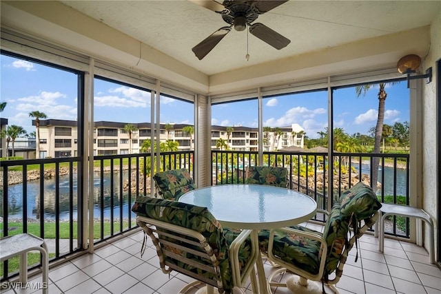 sunroom / solarium with ceiling fan and a water view