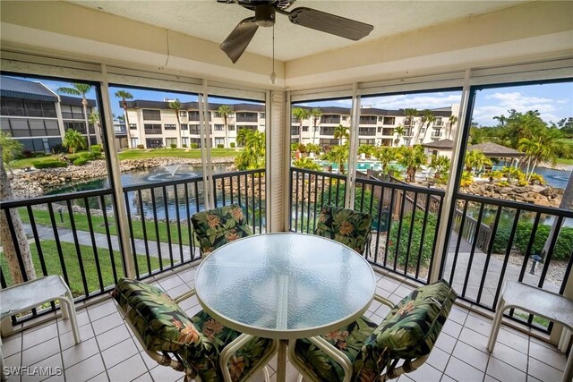 sunroom with a wealth of natural light, a water view, and ceiling fan