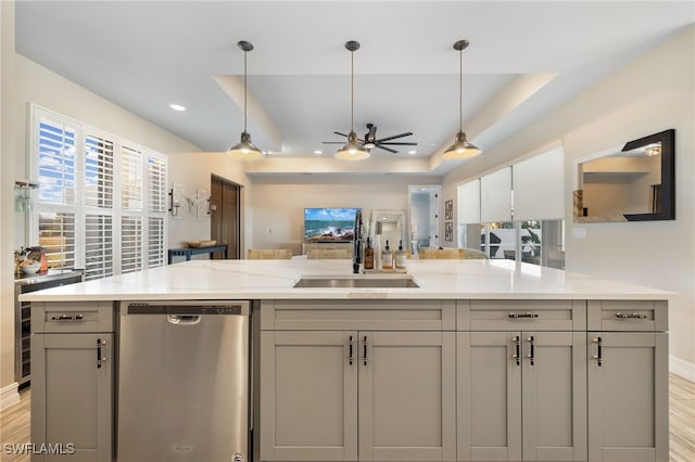 kitchen featuring dishwasher, a raised ceiling, hanging light fixtures, and sink