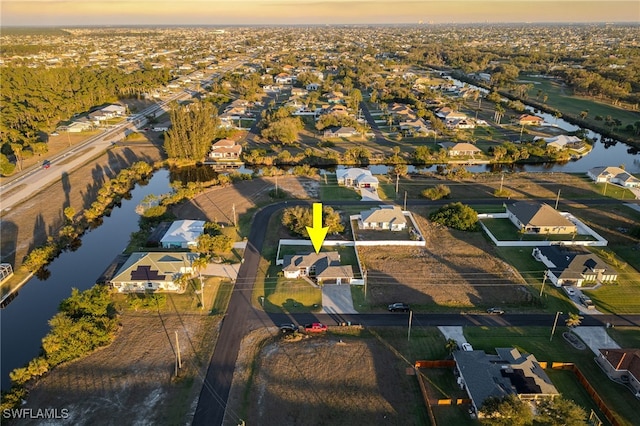 aerial view at dusk featuring a water view