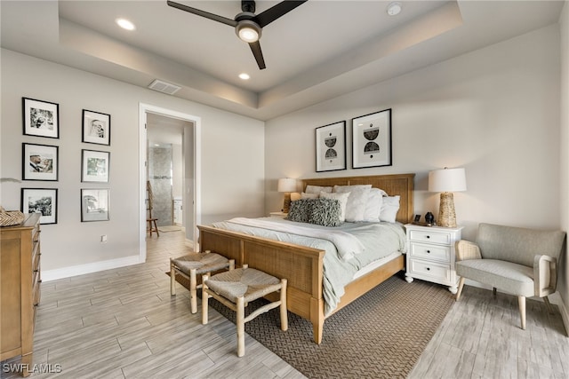 bedroom featuring ensuite bathroom, ceiling fan, and a tray ceiling