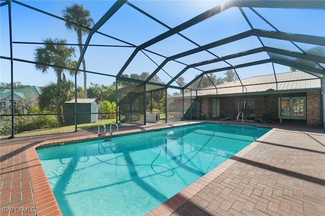 view of pool featuring a patio area, a lanai, and a storage shed