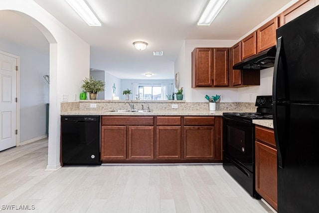 kitchen featuring kitchen peninsula, light stone counters, sink, black appliances, and light hardwood / wood-style flooring