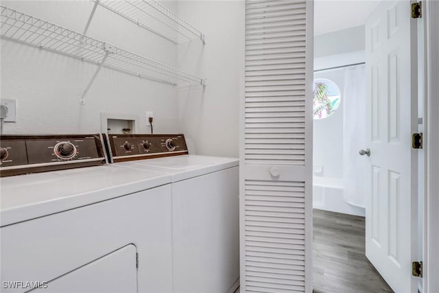 washroom with washing machine and clothes dryer and wood-type flooring