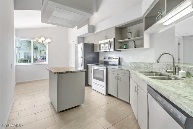 kitchen with sink, light stone counters, a center island, pendant lighting, and stainless steel appliances