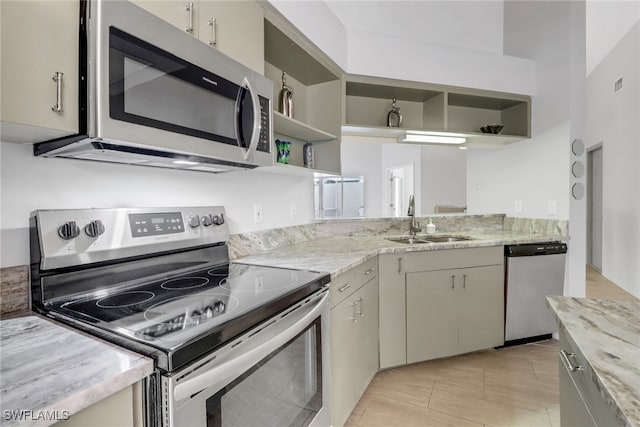 kitchen featuring light stone counters, stainless steel appliances, and sink