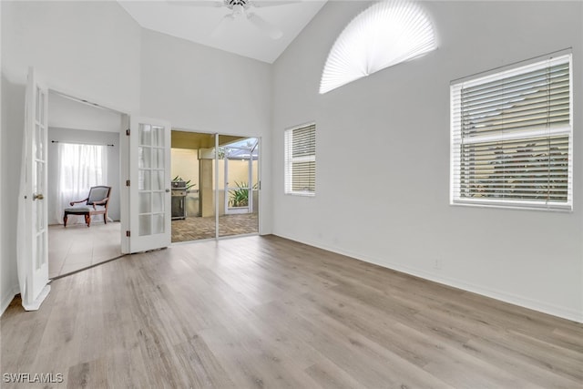 spare room with ceiling fan, high vaulted ceiling, light wood-type flooring, and french doors