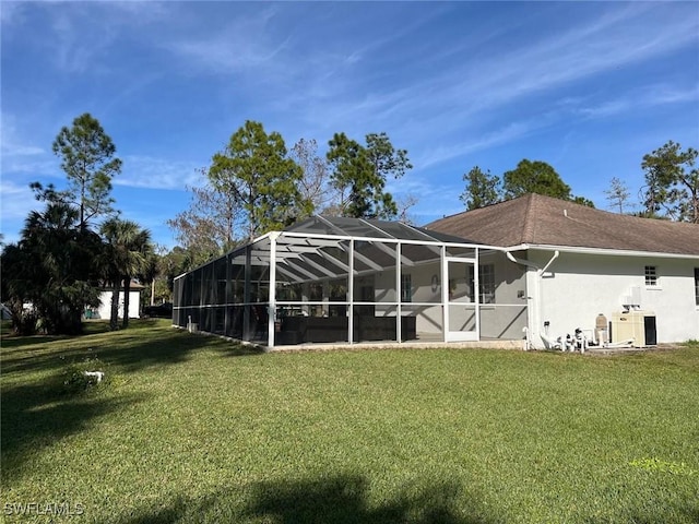 rear view of house with a yard and a lanai