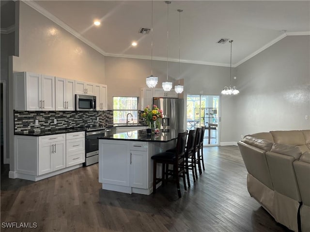 kitchen featuring appliances with stainless steel finishes, a kitchen island, hanging light fixtures, and white cabinets