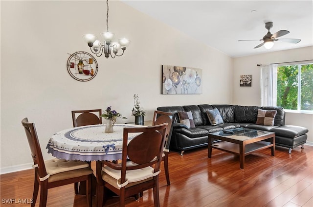 dining space with hardwood / wood-style floors, ceiling fan with notable chandelier, and vaulted ceiling