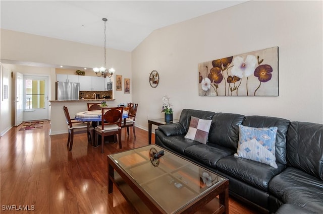 living room with an inviting chandelier, vaulted ceiling, and dark hardwood / wood-style floors