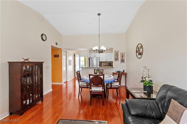 dining space with a notable chandelier, vaulted ceiling, and hardwood / wood-style flooring