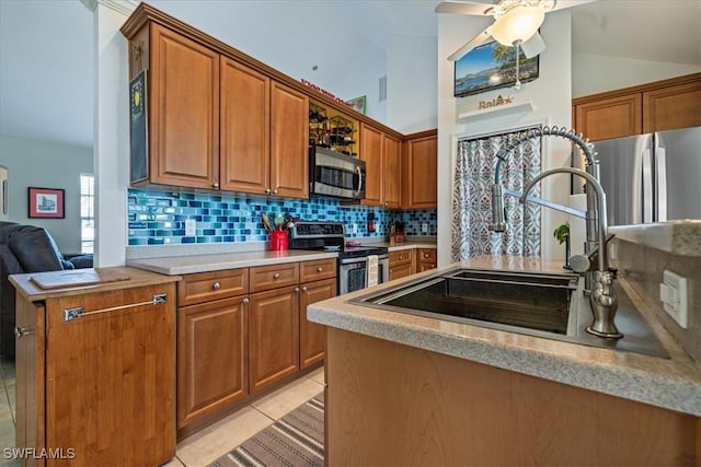 kitchen featuring decorative backsplash, appliances with stainless steel finishes, vaulted ceiling, sink, and light tile patterned floors