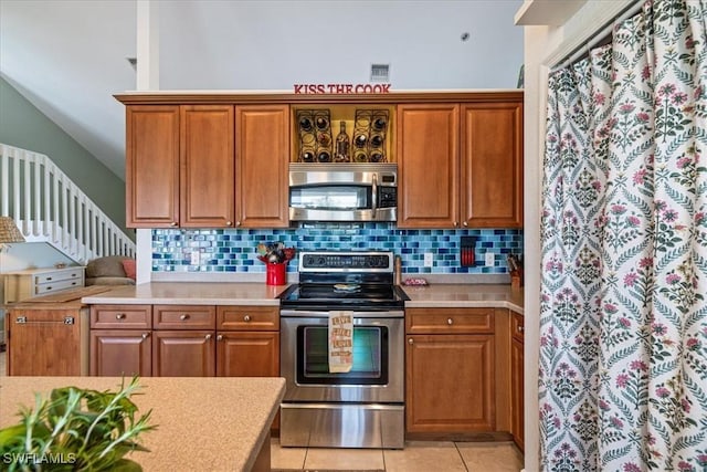 kitchen with backsplash, light tile patterned flooring, and stainless steel appliances