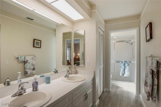 bathroom with hardwood / wood-style floors, vanity, and a shower with door