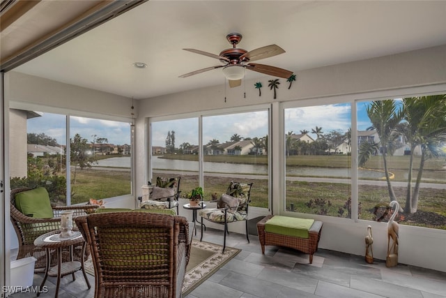 sunroom with a water view, a wealth of natural light, and ceiling fan