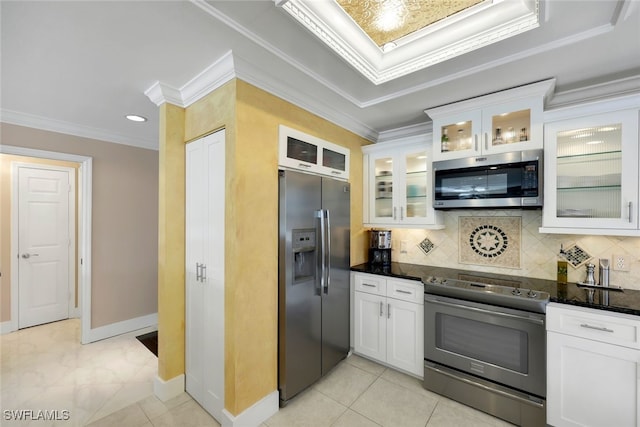 kitchen with white cabinets, dark stone countertops, ornamental molding, appliances with stainless steel finishes, and tasteful backsplash