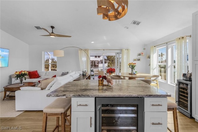 kitchen featuring white cabinetry, beverage cooler, and light stone counters