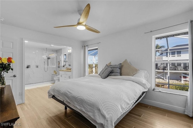 bedroom featuring ceiling fan, light hardwood / wood-style floors, and multiple windows