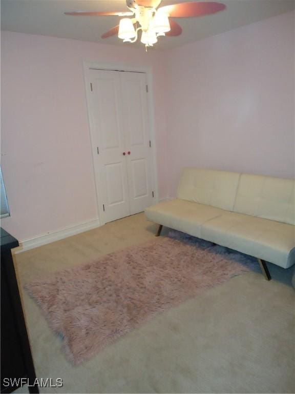 living area with ceiling fan and light carpet