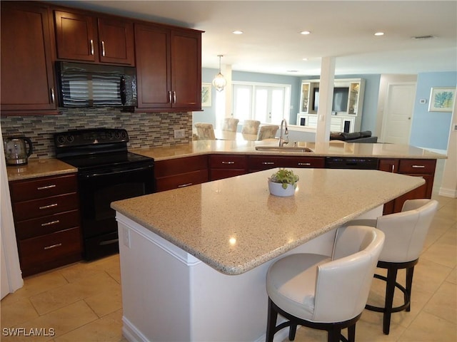 kitchen featuring black appliances, a kitchen breakfast bar, sink, decorative backsplash, and kitchen peninsula