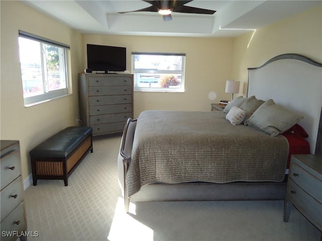 carpeted bedroom featuring a raised ceiling and ceiling fan