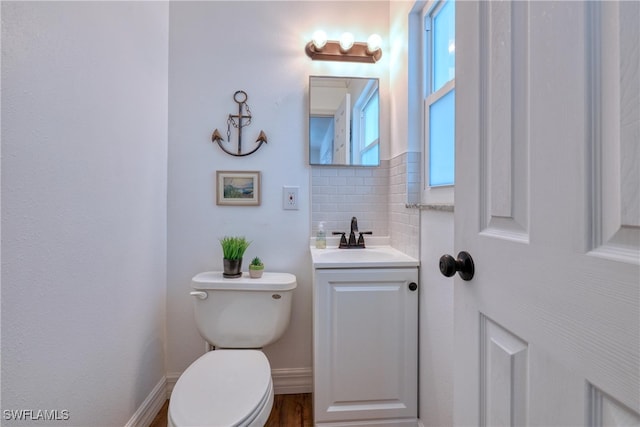 bathroom featuring toilet, vanity, and decorative backsplash