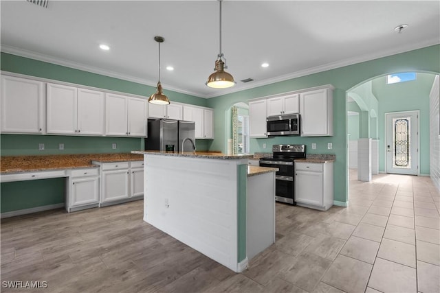 kitchen featuring appliances with stainless steel finishes, light stone counters, a kitchen island with sink, decorative light fixtures, and white cabinets