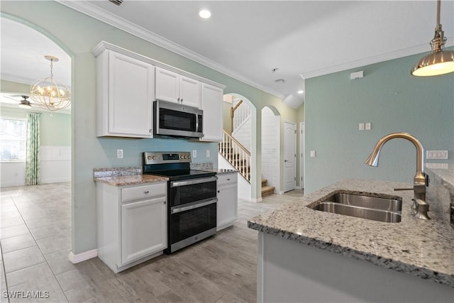 kitchen featuring ornamental molding, arched walkways, appliances with stainless steel finishes, and a sink