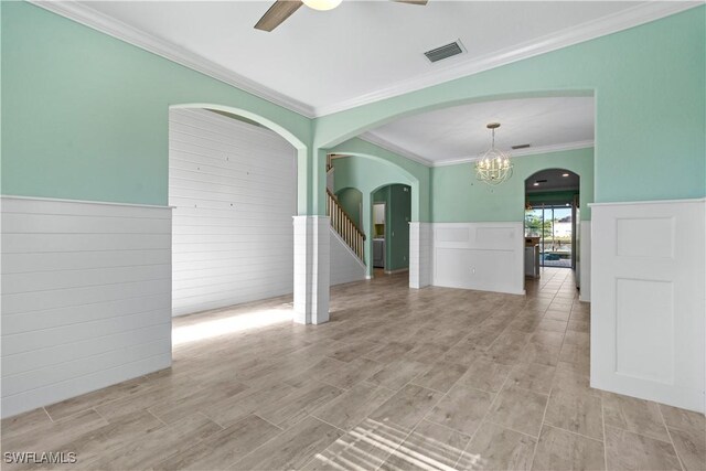 unfurnished room with ceiling fan with notable chandelier and crown molding