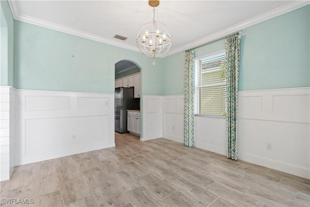 empty room with visible vents, a wainscoted wall, arched walkways, crown molding, and a chandelier