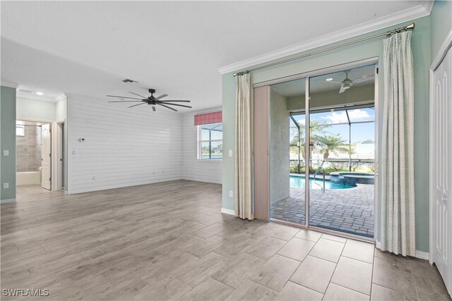 unfurnished living room with ceiling fan and crown molding