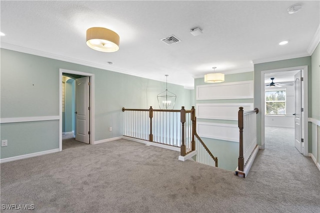 corridor with visible vents, an upstairs landing, carpet floors, and crown molding