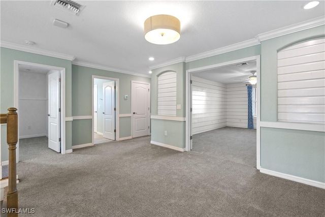 empty room with crown molding, baseboards, visible vents, and carpet floors