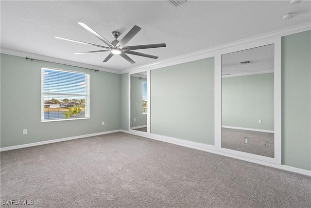 empty room featuring carpet flooring, baseboards, ceiling fan, and ornamental molding