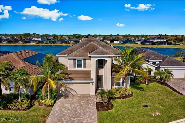 view of front of home with a front yard, a water view, and a garage