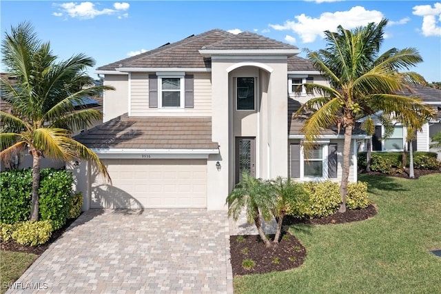 view of front of house with decorative driveway, a garage, a front lawn, and stucco siding