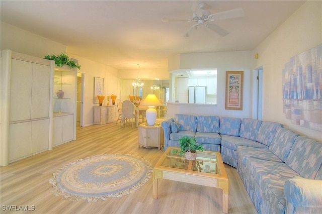 living room with ceiling fan with notable chandelier and light wood-type flooring