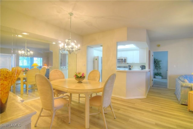 dining room with light wood-style floors and an inviting chandelier