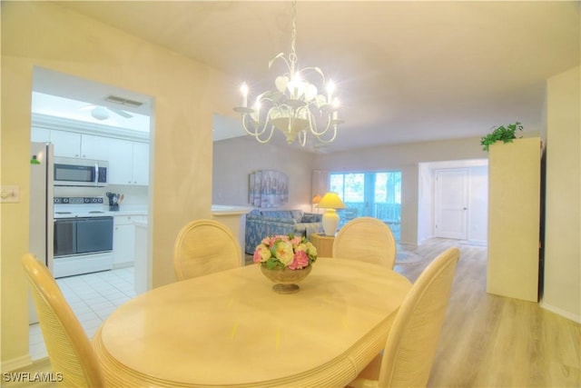 dining space featuring light hardwood / wood-style flooring and an inviting chandelier